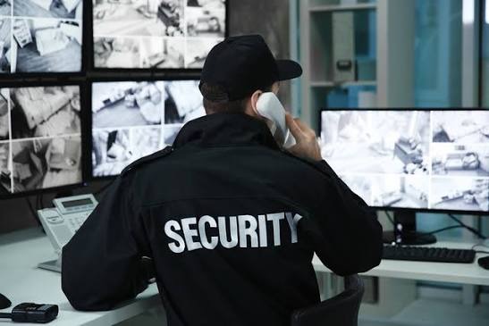 A dark, sophisticated security operations center with a wall of glowing monitors displaying high-resolution surveillance feeds.