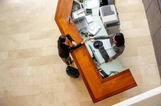 A high-end corporate lobby with minimalist marble floors and a sleek glass reception desk, with a professionally dressed security officer standing discreetly in the background.